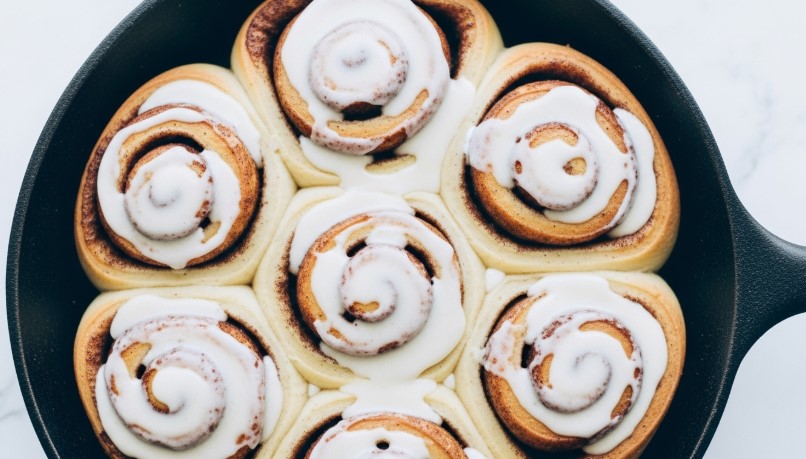 baked sourdough discard cinnamon rolls in skillet with icing