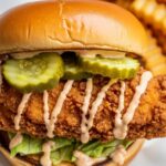 golden fried chicken sandwich with pickles and sauce