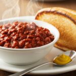 Thick hot dog chili with mustard served beside a toasted bun