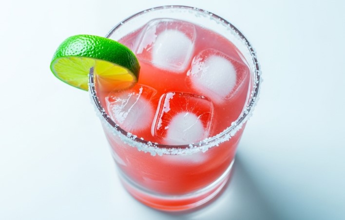strawberry margarita on the rocks with lime garnish